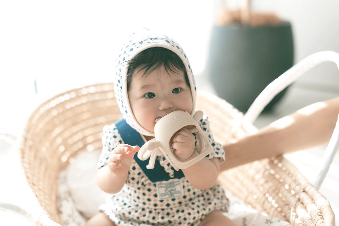 手首にはめたBerpyの歯固めを口に運ぶ赤ちゃん